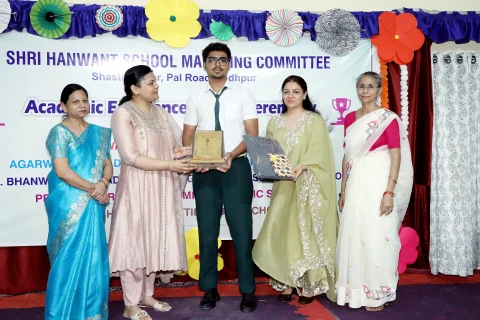 Senior student receiving an award from Mrs. Madhuri Singhal and Ms. Prerna Singhal